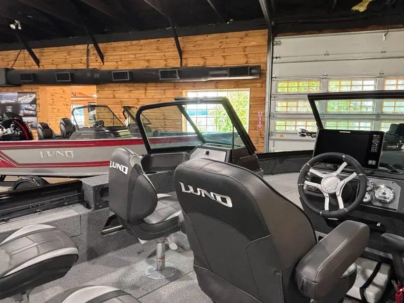 Slide: The Image of 2025 Lund 2025 Impact XS Sport boat interior with steering wheel and seating in showroom. - 12