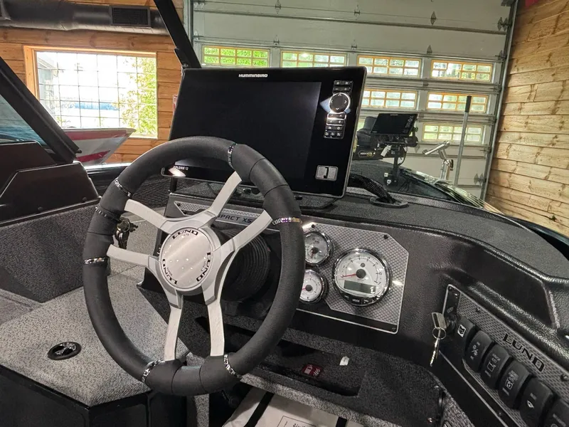 Slide: The Image of 2025 Lund 2025 Impact XS Sport boat dashboard with steering wheel and electronic display. - 13