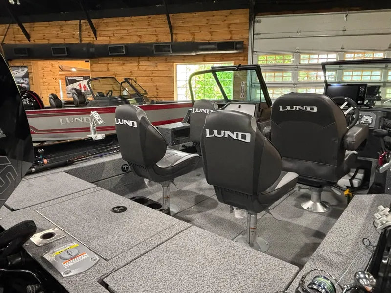 Slide: The Image of 2025 Lund 2025 Impact XS Sport boat interior with seating and controls in showroom. - 14
