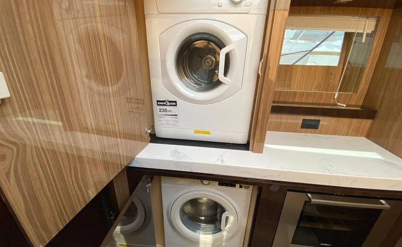 Slide: The Image of Laundry area in 2022 Cruisers Yachts 60 Fly, featuring modern appliances and wood cabinetry. - 41