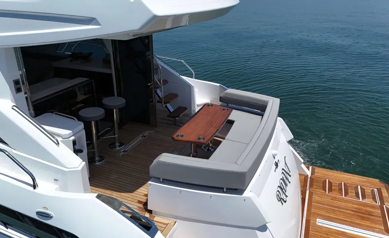 Slide: The Image of 2022 Cruisers Yachts 60 Fly, luxurious deck with seating and table, overlooking serene water. - 8