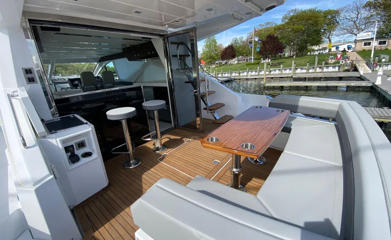 Slide: The Image of 2022 Cruisers Yachts 60 Fly deck with seating, table, and bar stools, docked by the water. - 13