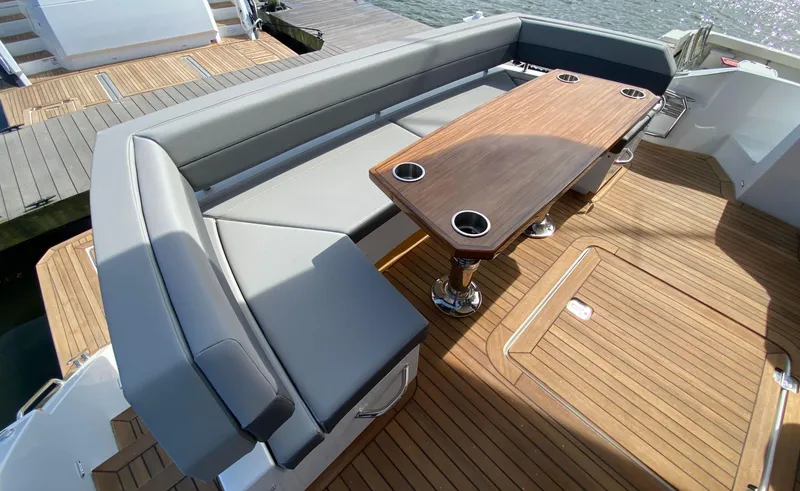 Slide: The Image of Luxurious seating area on 2022 Cruisers Yachts 60 Fly with wooden table and cup holders. - 18