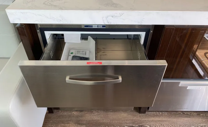 Slide: The Image of Open drawer refrigerator in 2022 Cruisers Yachts 60 Fly kitchen area. - 25