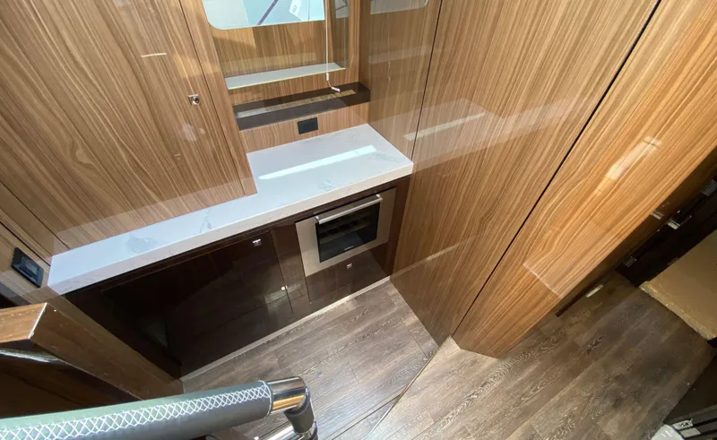 Slide: The Image of Modern kitchen area in 2022 Cruisers Yachts 60 Fly with wood paneling and built-in oven. - 38