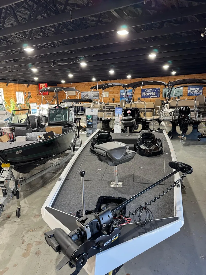 Slide: The Image of 2025 Lund 1975 Renegade SS boat in showroom, surrounded by various other boats. - 2
