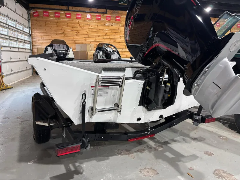 Slide: The Image of 2025 Lund 1975 Renegade SS boat in garage, featuring outboard motor and trailer. - 22