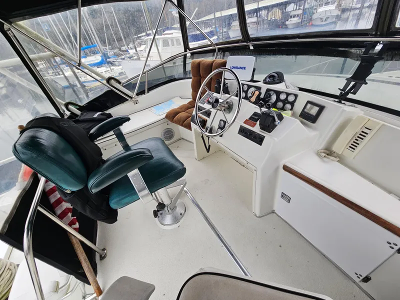 Slide: The Image of 1991 Tollycraft Euro Sport Sedan helm with steering wheel, controls, and seating in a marina setting. - 22