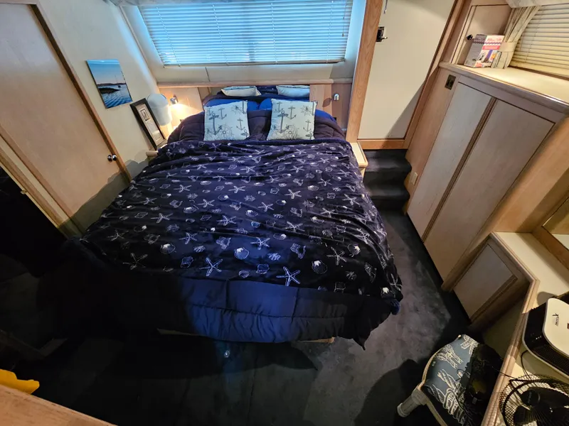 Slide: The Image of 1991 Tollycraft Euro Sport Sedan bedroom with nautical-themed bedding and wooden cabinetry. - 35