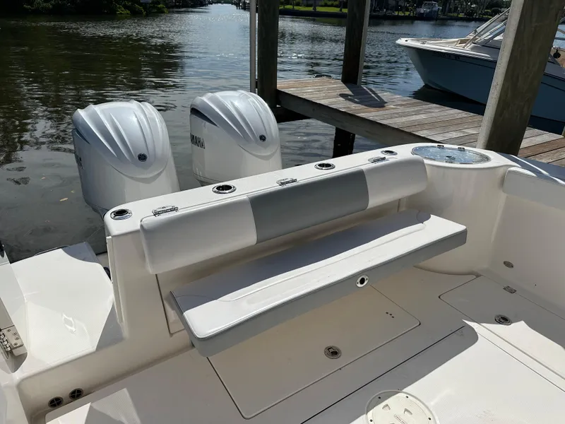 Slide: The Image of 2021 Robalo R302 Center Console boat with dual Yamaha engines docked by the water. - 14