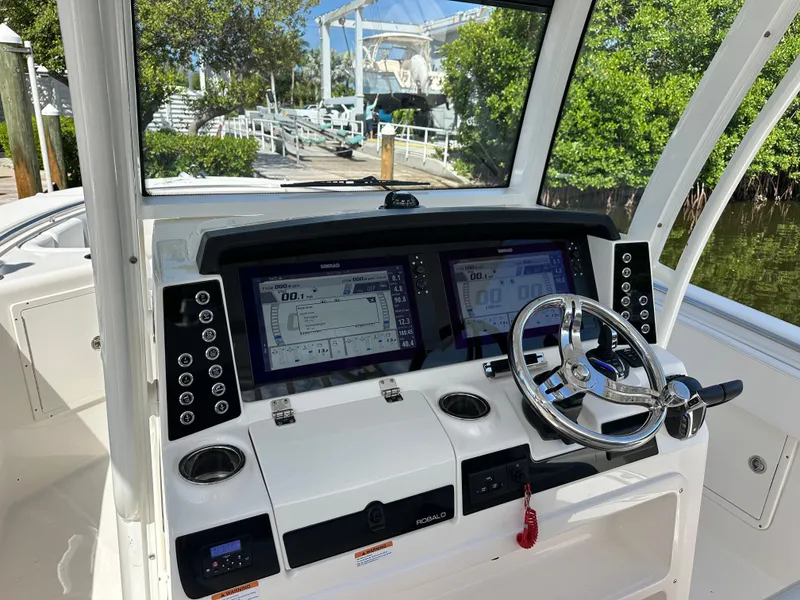 Slide: The Image of 2021 Robalo R302 Center Console boat dashboard with dual displays and steering wheel. - 5