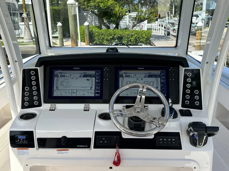 Slide: The Image of 2021 Robalo R302 Center Console boat dashboard with dual displays and steering wheel. - 8
