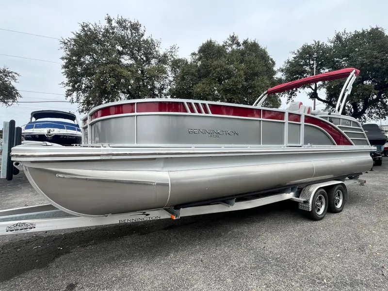 The Image of 2024 Bennington 25LTFB pontoon boat on trailer, silver and red design. - 0