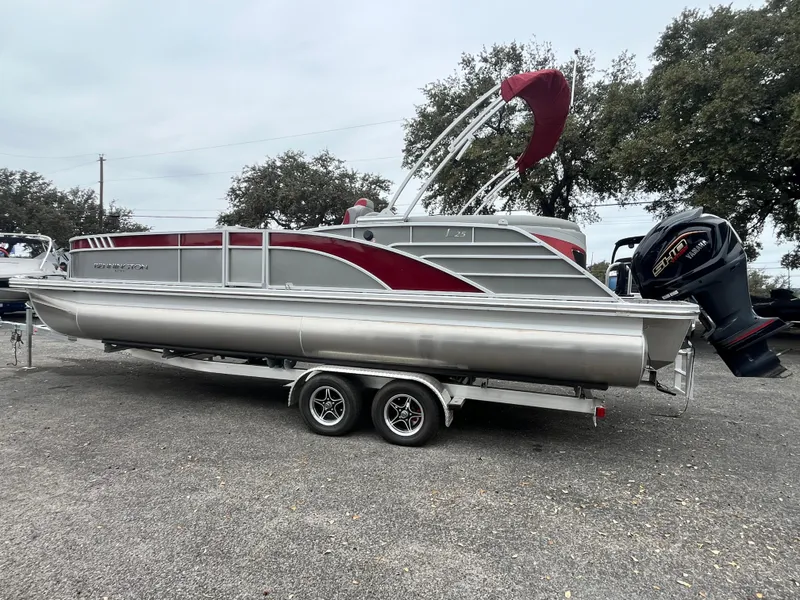 Slide: The Image of 2024 Bennington 25LTFB pontoon boat with red accents on a trailer. - 1