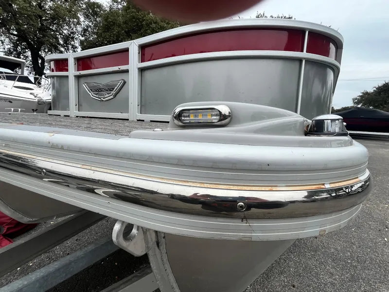 Slide: The Image of 2024 Bennington 25LTFB pontoon boat, silver and red exterior, docked outdoors. - 2