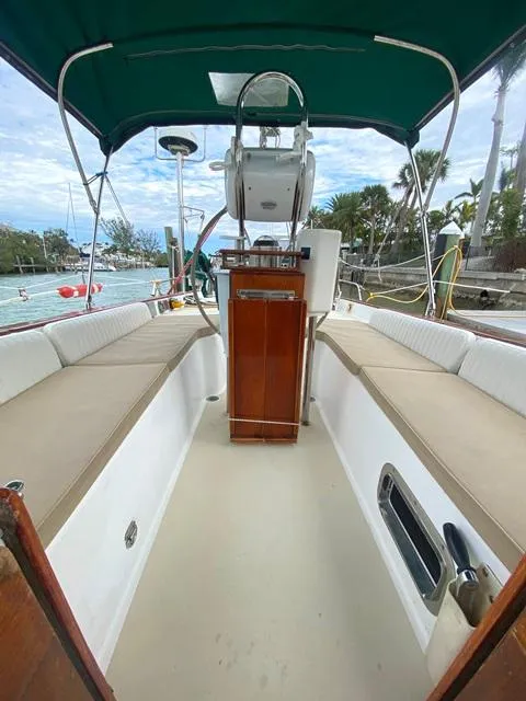 Slide: The Image of 1992 Freedom 45 sailboat cockpit with green canopy and wooden helm, docked by palm trees. - 21
