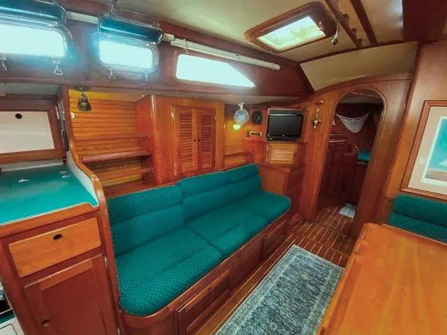 Slide: The Image of Cozy 1992 Freedom 45 yacht interior with teal seating, wood paneling, and compact kitchen area. - 26