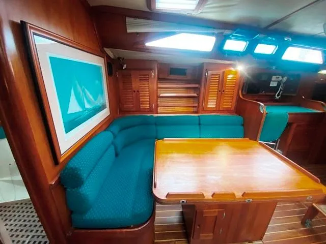 Slide: The Image of Cozy 1992 Freedom 45 yacht interior with teal seating, wooden table, and nautical artwork. - 28