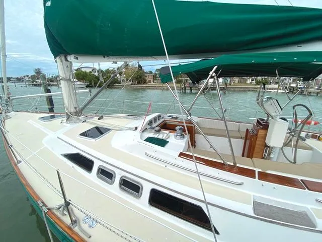 Slide: The Image of Sailboat Freedom 45, 1992 model, docked with green canopy and scenic waterfront view. - 3
