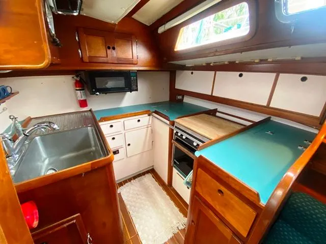 Slide: The Image of Cozy 1992 Freedom 45 boat kitchen with teal countertops, wooden cabinets, and modern appliances. - 31