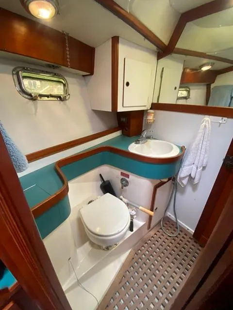 Slide: The Image of Compact boat bathroom with teal accents, wooden trim, and porthole window in a 1992 Freedom 45. - 38