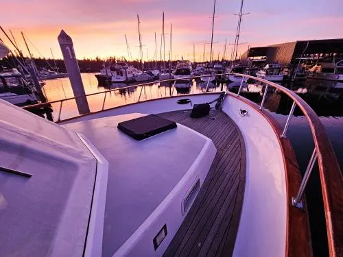 Slide: The Image of 1983 Ocean Alexander 43 yacht at sunset in marina, showcasing deck and serene water reflections. - 10