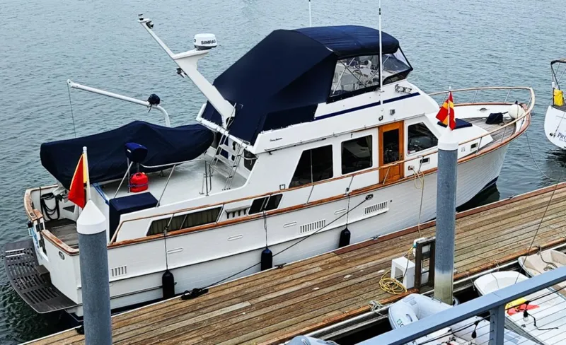 Slide: The Image of 1983 Ocean Alexander 43 yacht docked at marina, featuring classic design and navy canopy. - 3