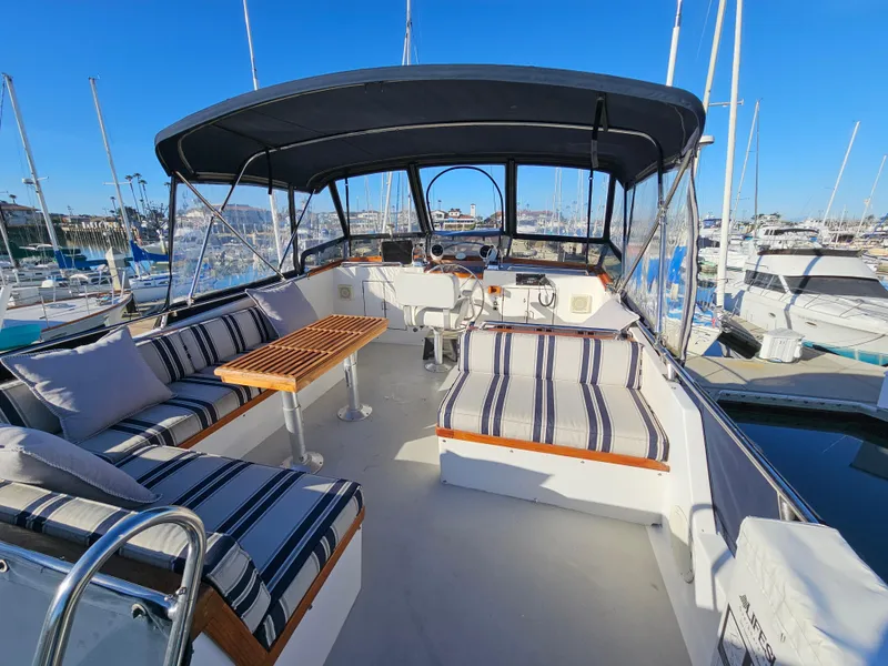 Slide: The Image of 1983 Ocean Alexander 43 yacht with striped seating and canopy in a marina. - 7