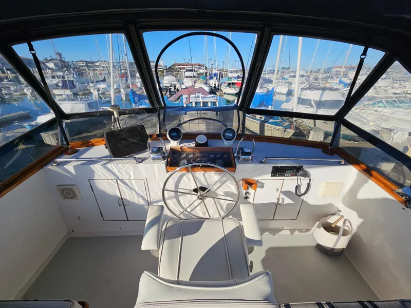 Slide: The Image of Cockpit view of 1983 Ocean Alexander 43 yacht, featuring steering wheel and marina backdrop. - 8