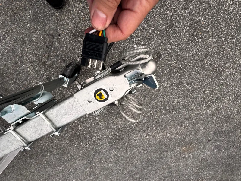 Slide: The Image of Hand holding trailer connector near hitch, 2025 Single Axle Trailer model. - 14