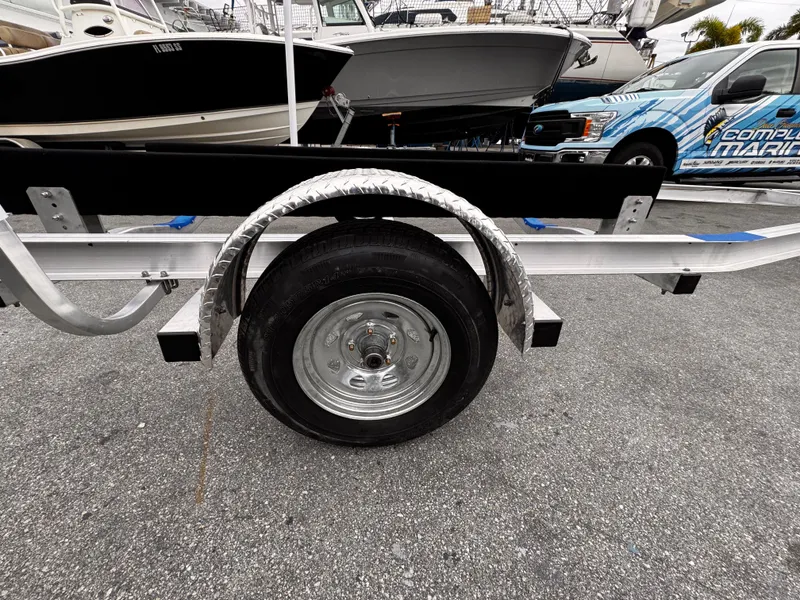 Slide: The Image of 2025 Single Axle Trailer with wheel, parked on asphalt near boats and vehicles. - 4