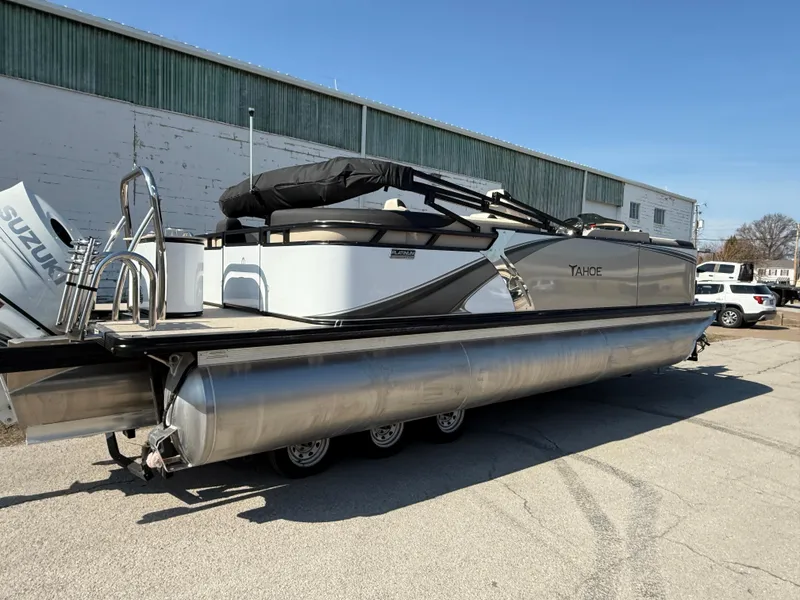 Slide: The Image of 2025 Tahoe Pontoon LTZ Quad Lounger on trailer, parked outdoors. - 3
