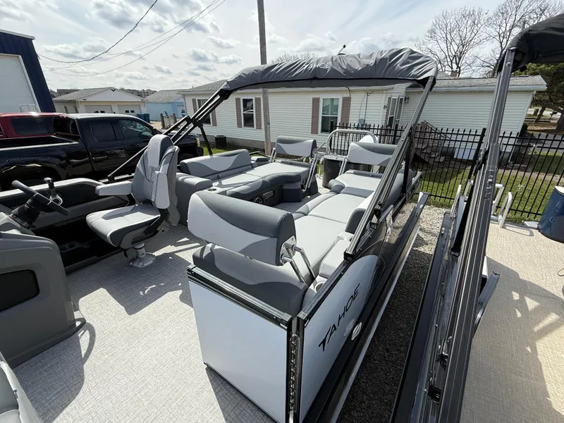 Slide: The Image of 2025 Tahoe Pontoon LTZ Quad Lounger Shift with gray seating and canopy, parked outdoors. - 5