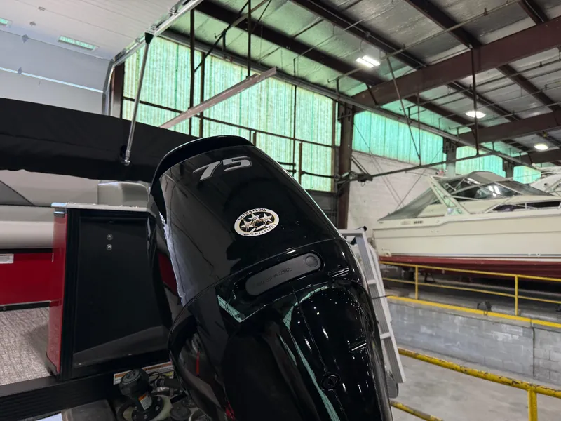 Slide: The Image of 2025 Tahoe Pontoon Sport 85 Cruise Rear Bench with 75 HP engine in a warehouse. - 10