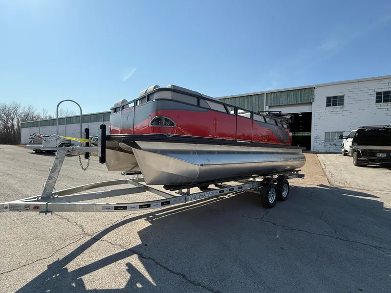 Slide: The Image of 2025 Tahoe Pontoon Sport 85 Cruise Rear Bench on trailer, parked outside a warehouse. - 2