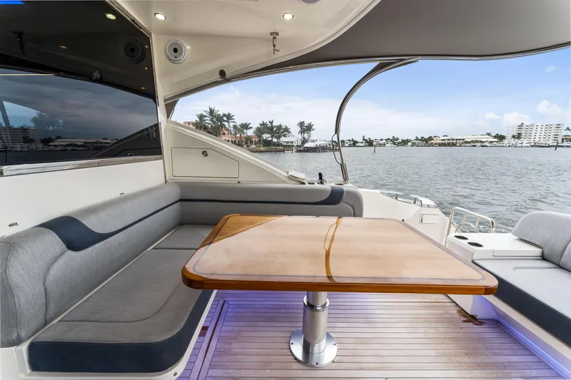 Slide: The Image of 2021 Riviera 5400 Sport Yacht interior with elegant seating and wooden table, overlooking serene waters. - 22