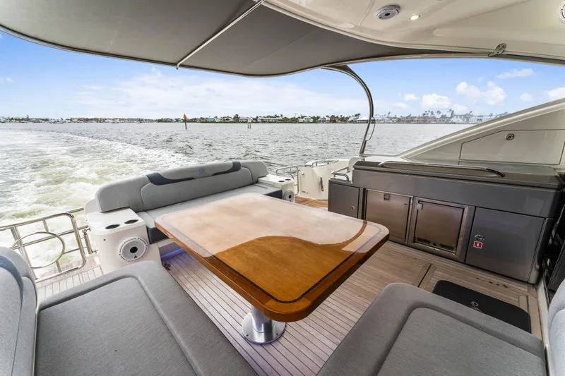 Slide: The Image of 2021 Riviera 5400 Sport Yacht, luxurious deck with seating and table, cruising on water. - 24