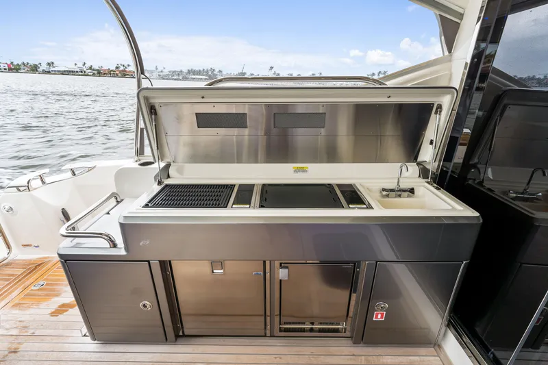 Slide: The Image of Outdoor kitchen on 2021 Riviera 5400 Sport Yacht, featuring grill and sink by the water. - 26