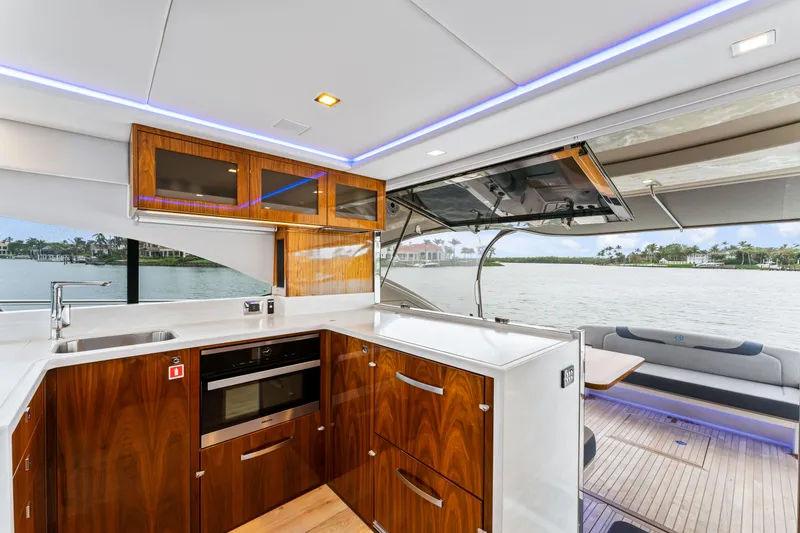 Slide: The Image of Luxurious 2021 Riviera 5400 Sport Yacht kitchen with wood cabinetry and waterfront view. - 39