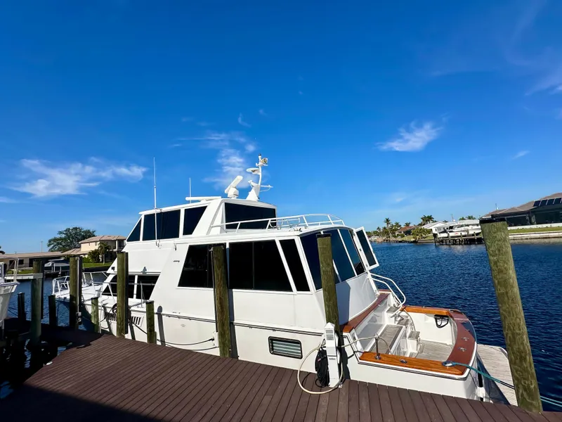 Slide: The Image of 1999 Viking 60 Cockpit Sports Yacht docked by a serene waterfront under a clear blue sky. - 2