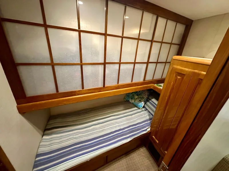 Slide: The Image of 1999 Viking 60 Cockpit Sports Yacht cabin with wooden accents and striped bedding. - 26