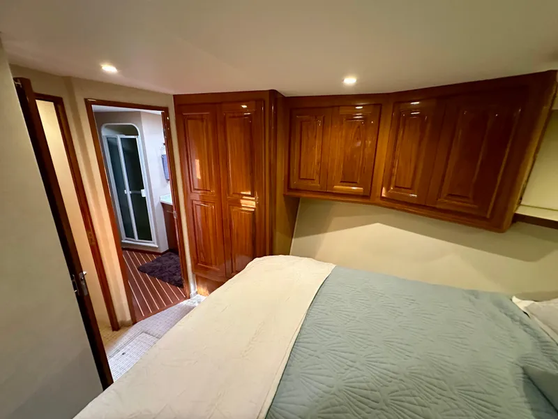 Slide: The Image of Bedroom interior of 1999 Viking 60 Cockpit Sports Yacht with wooden cabinets and cozy bedding. - 31