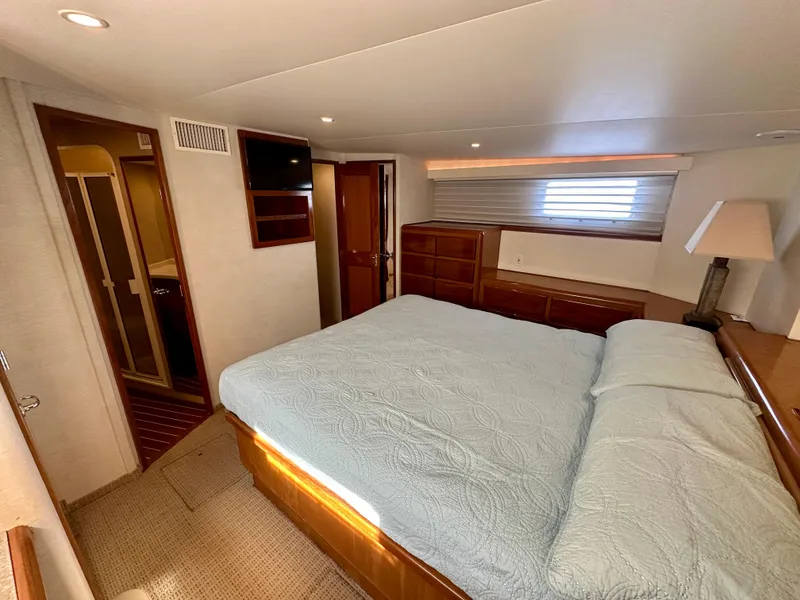 Slide: The Image of Luxurious bedroom interior of 1999 Viking 60 Cockpit Sports Yacht with cozy bed and wooden furnishings. - 39