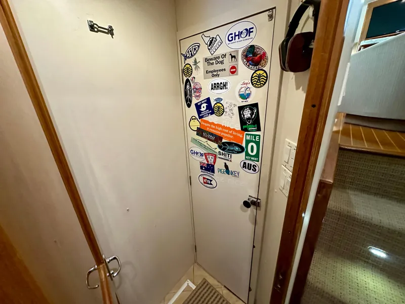 Slide: The Image of Door covered in colorful stickers inside a 1999 Viking 60 Cockpit Sports Yacht. - 41
