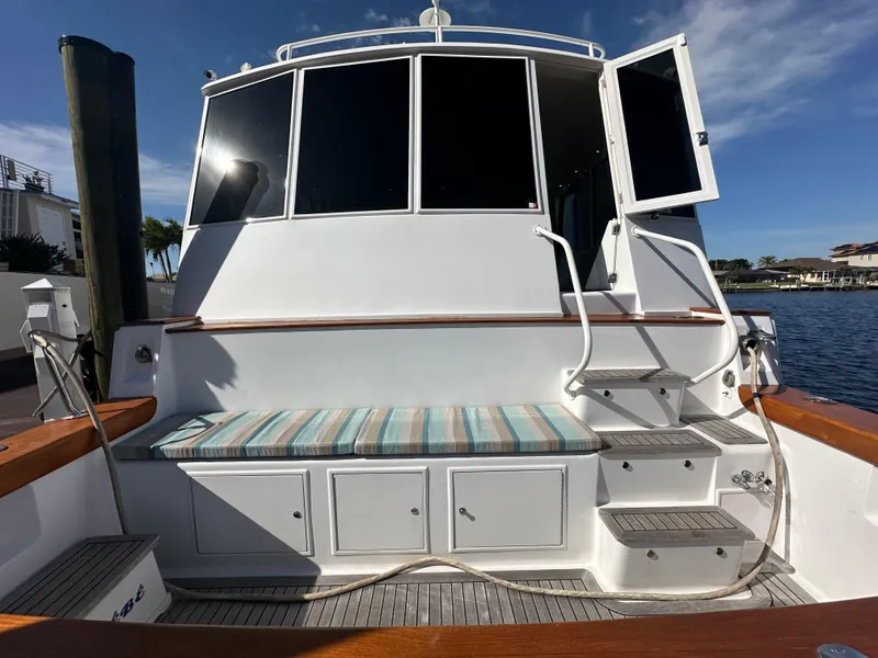Slide: The Image of 1999 Viking 60 Cockpit Sports Yacht with striped seating and open door, docked by the water. - 5