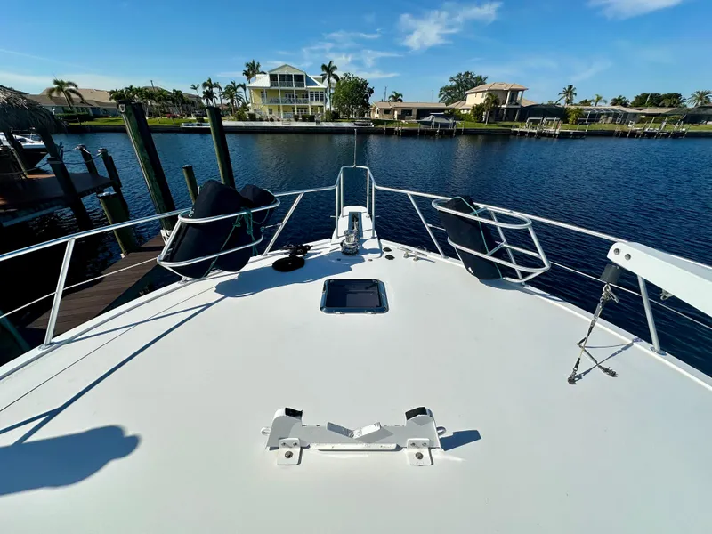 Slide: The Image of Bow view of 1999 Viking 60 Cockpit Sports Yacht docked by waterfront homes. - 7