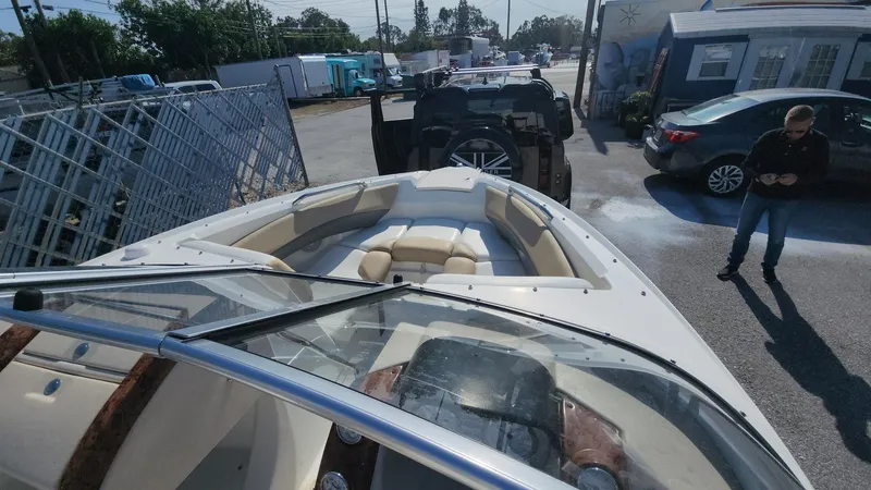 Slide: The Image of 2005 Larson LXi 208 boat in a parking lot, with vehicles and a person nearby. - 22