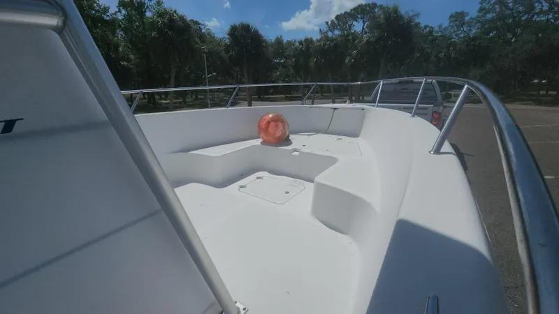 Slide: The Image of 2003 Pro-Line 22 boat deck with seating, railing, and orange buoy under clear sky. - 13