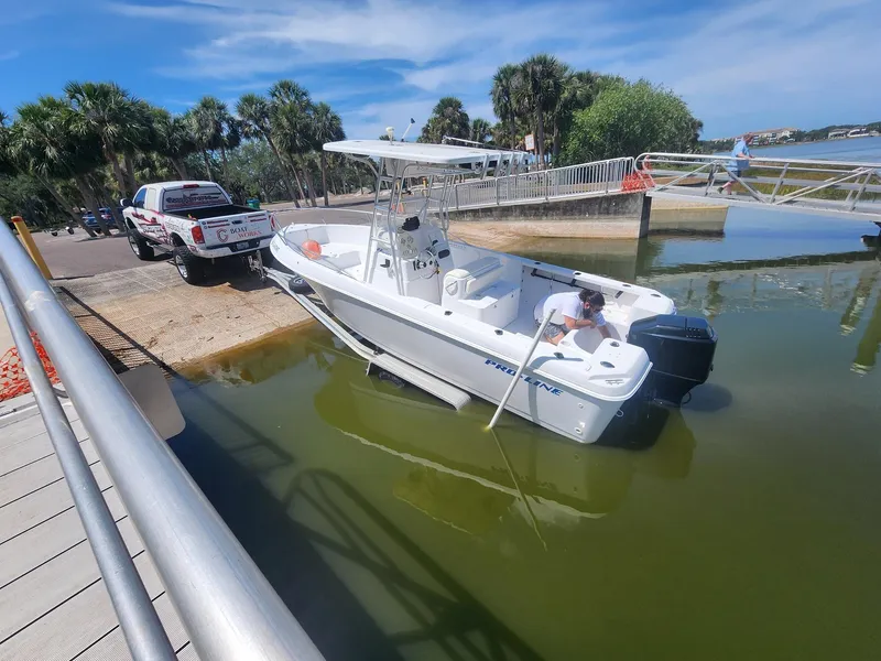 Slide: The Image of 2003 Pro-Line 22 boat being launched from a trailer at a sunny lakeside ramp. - 31