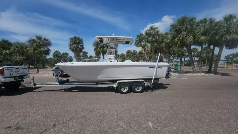 Slide: The Image of 2003 Pro-Line 22 boat on trailer, parked near palm trees under a clear blue sky. - 4